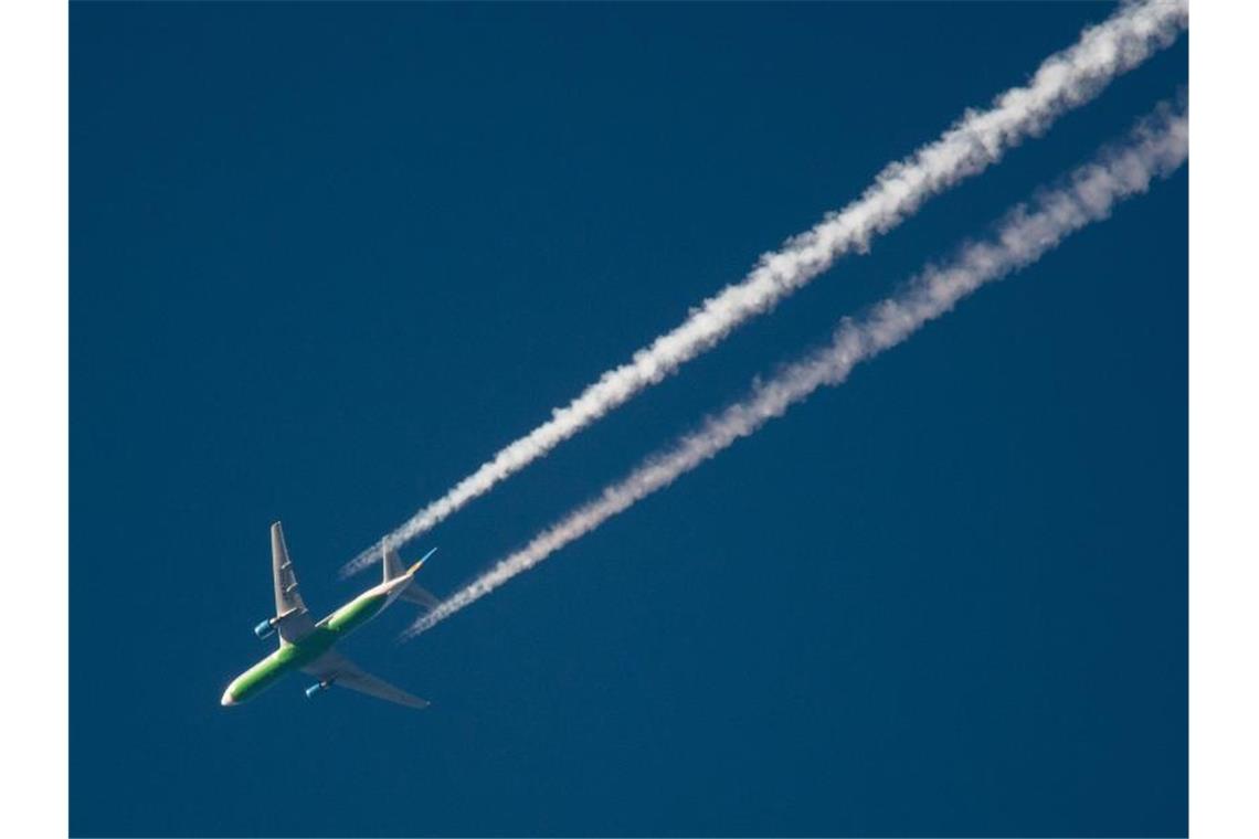 Ein Flugzeug hinterlässt am Himmel Kondensstreifen. Foto: Julian Stratenschulte/dpa