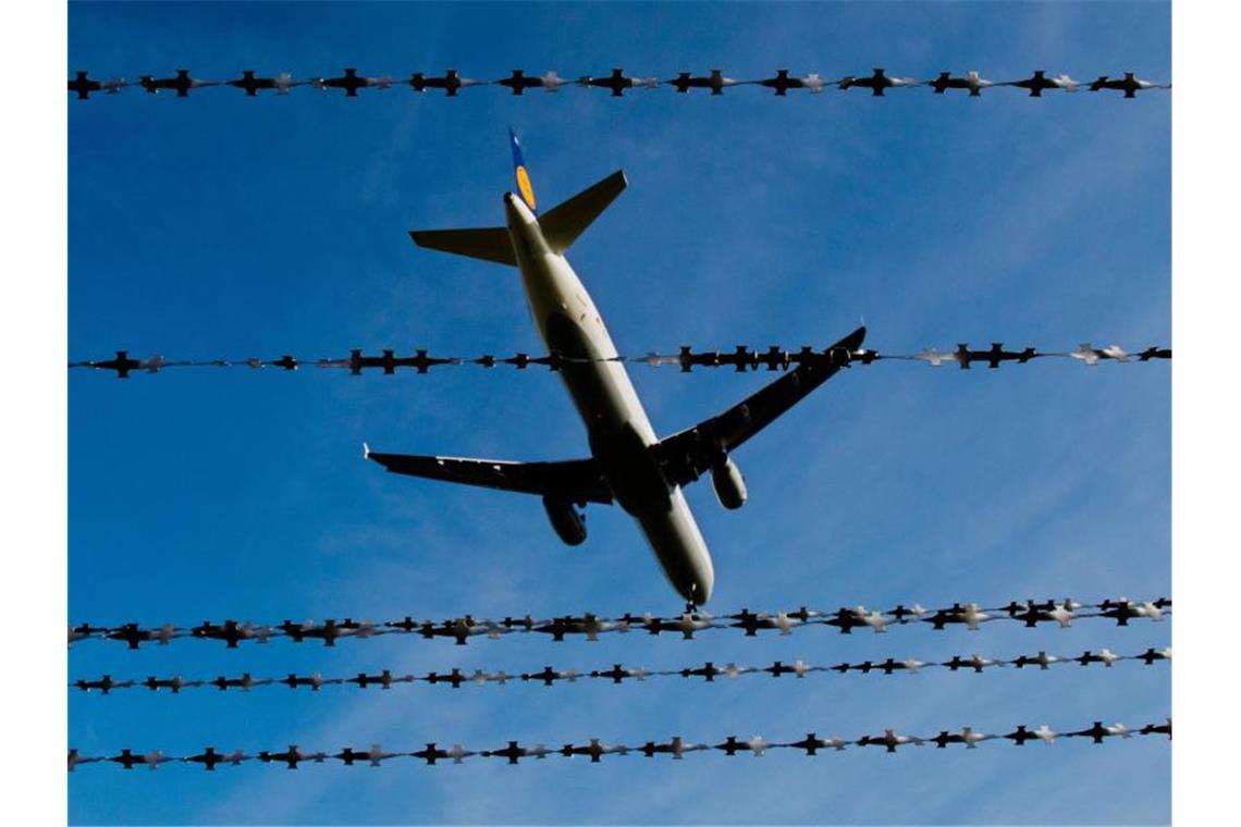 Ein Flugzeug ist am Flughafen hinter Stacheldraht zu sehen. Foto: Julian Stratenschulte/Archivbild