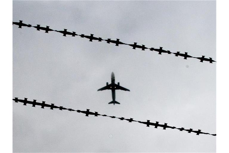 Ein Flugzeug ist hinter Stacheldraht zu sehen. Foto: Julian Stratenschulte/Archivbild