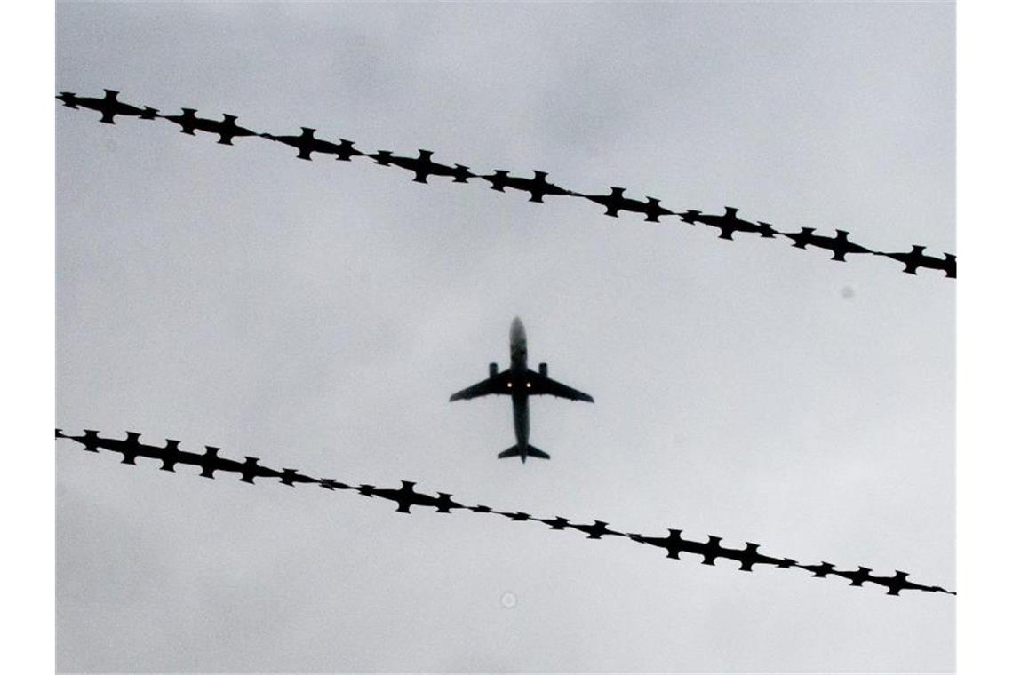 Ein Flugzeug ist hinter Stacheldraht zu sehen. Foto: Julian Stratenschulte/Archiv