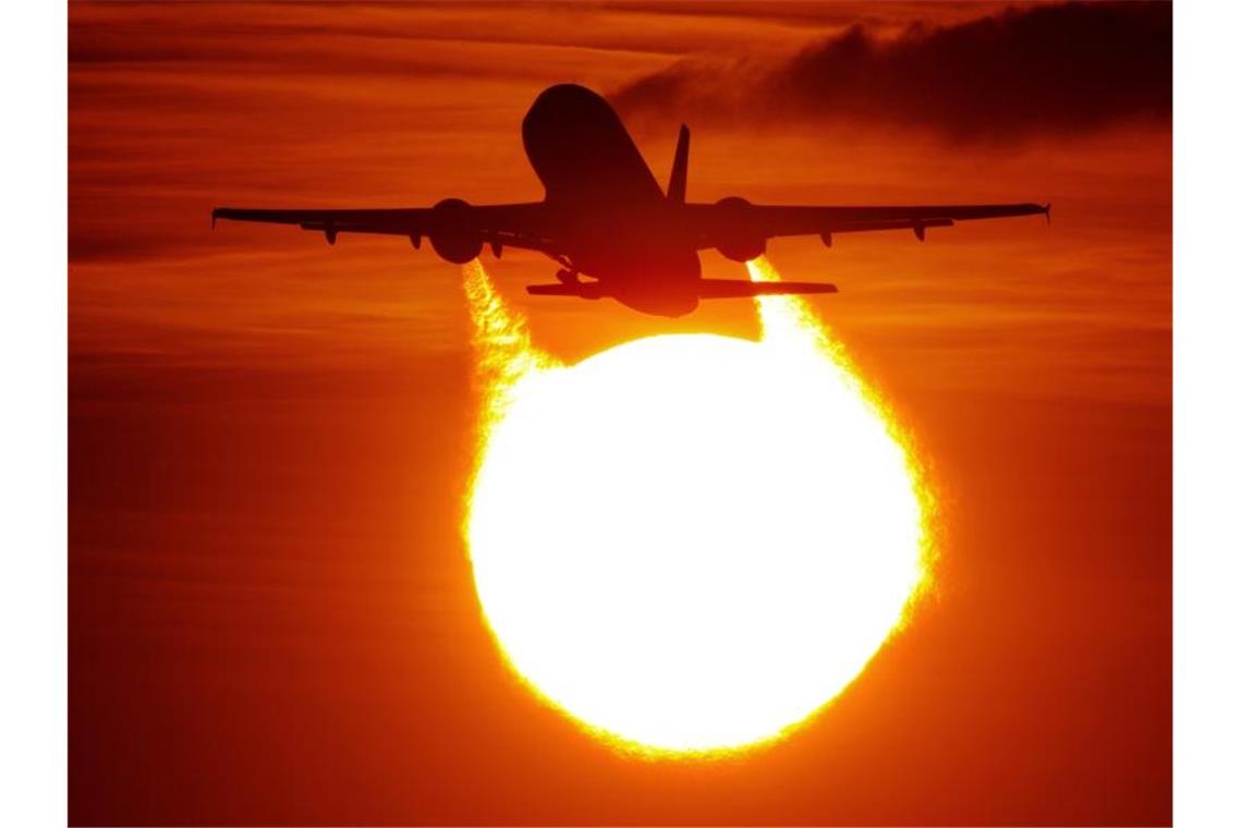 Ein Flugzeug startet am Flughafen vor der untergehenden Sonne. Foto: Julian Stratenschulte