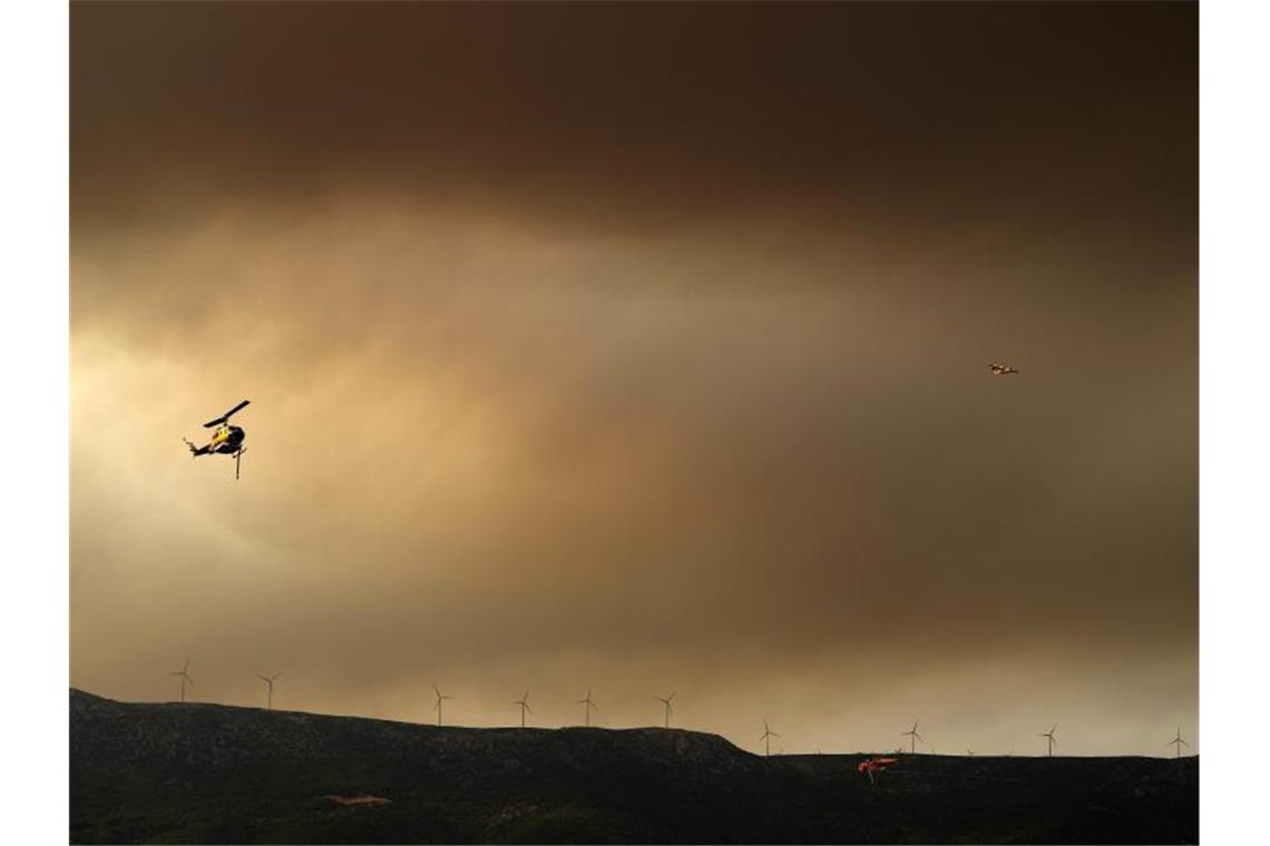 Griechischer Ort Vilia vor dem Feuer gerettet Ein Flugzeug und ein Hubschrauber unterstützen die Löscharbeiten. Foto: Thanassis Stavrakis/AP/dpa
