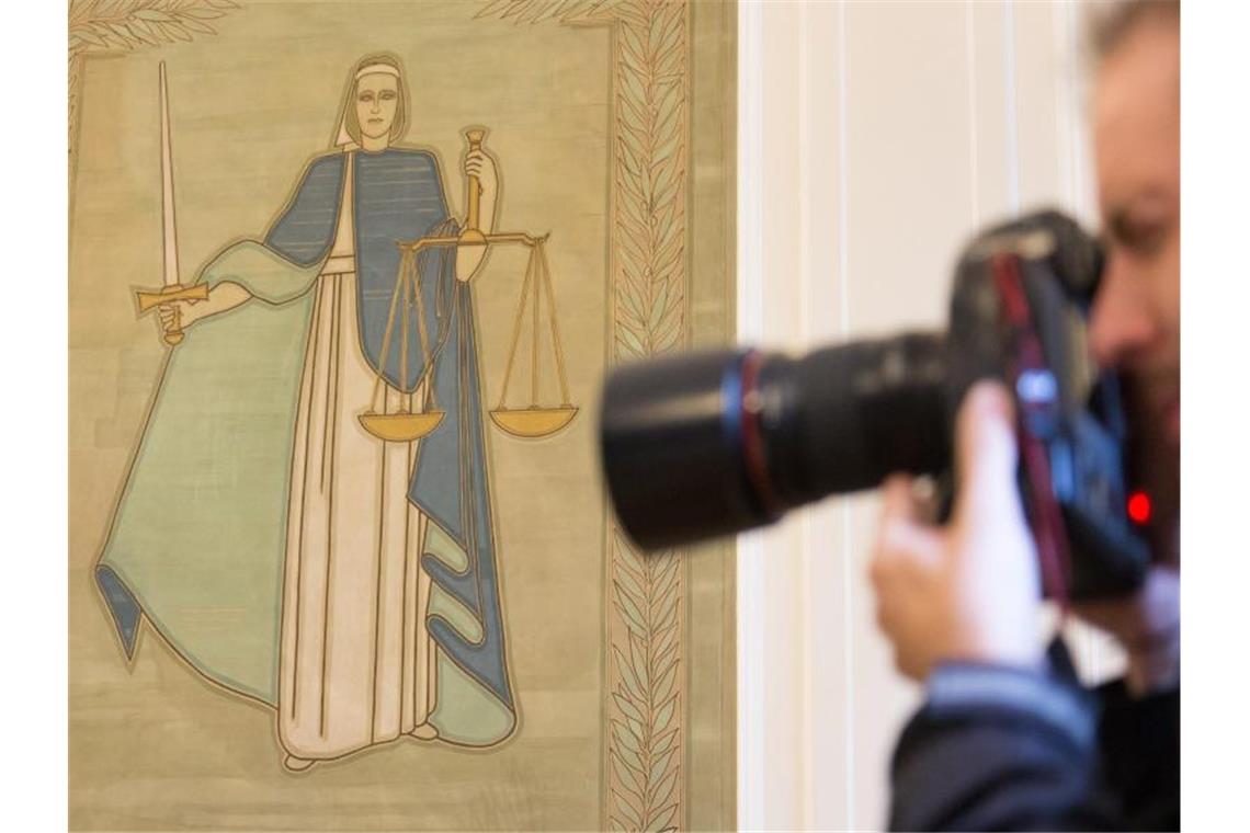 Ein Fotograf vor dem Bild der Justitia. Foto: Friso Gentsch/dpa/Archivbild