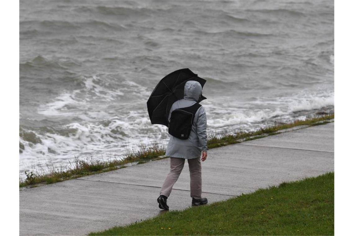Ein Frau geht bei Regen und Wind spazieren. Tief „Mortimer“ zieht von den Britischen Inseln über die Nordsee und weiter zur Ostsee. Foto: Carmen Jaspersen