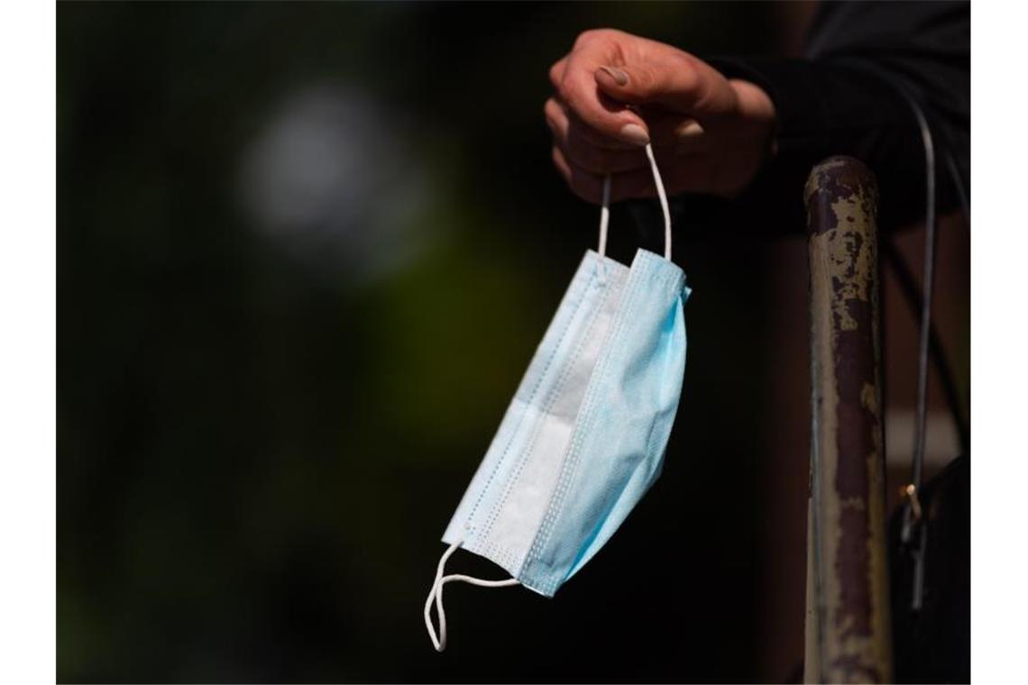Zahl der Infizierten in Europa steigt wieder Ein Frau hält vor einem Bäckereigeschäft ihren Mundschutz in der Hand. Foto: Robert Michael/dpa-Zentralbild/dpa