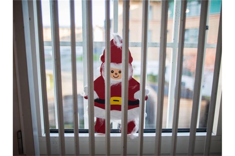 Ein gebastelter Weihnachtsmann klebt hinter einem Gitter einer Justizvollzugsanstalt an der Fensterscheibe. Foto: picture alliance/Frank Rumpenhorst/dpa/Symbolbild