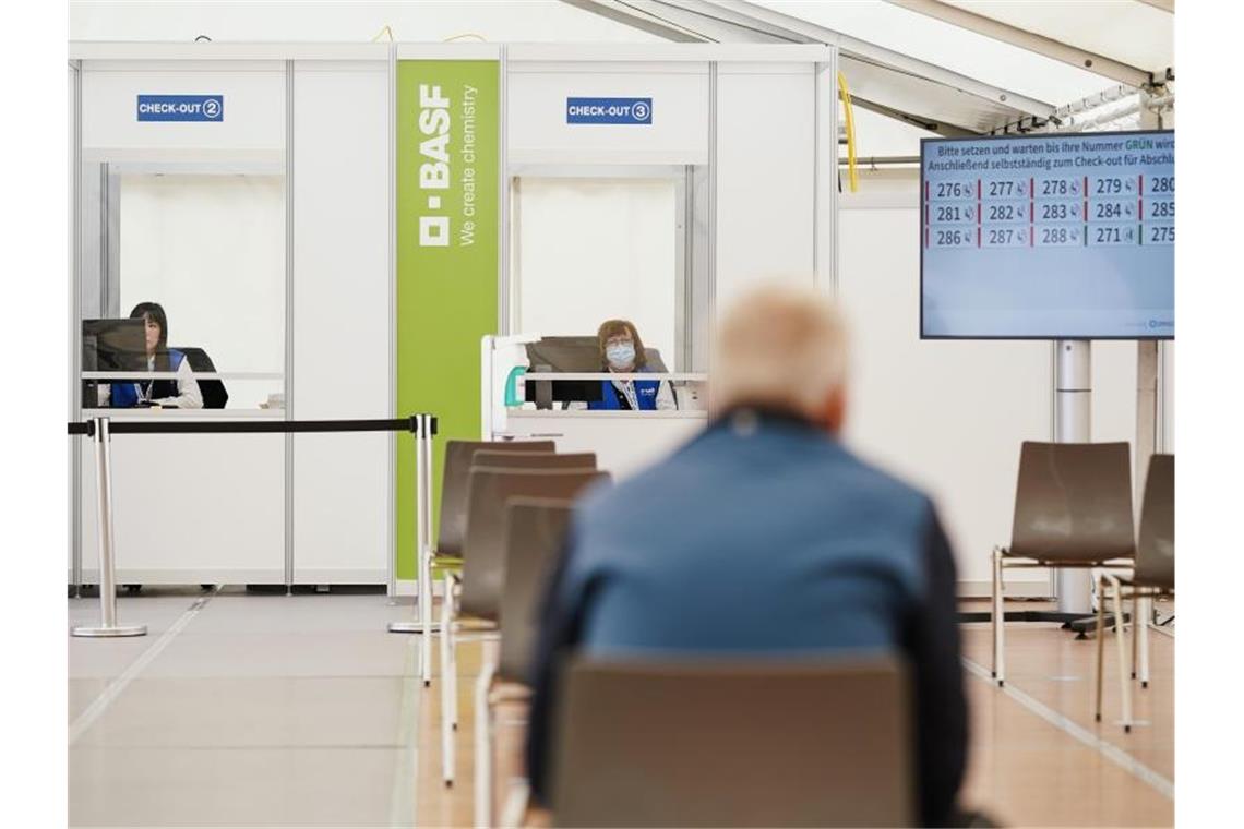 Ein geimpfter Mitarbeiter sitzt im BASF-Impfzentrum im Wartebereich, in dem mögliche Nebenwirkungen der Corona-Impfung beobachtet werden. Foto: Uwe Anspach/dpa