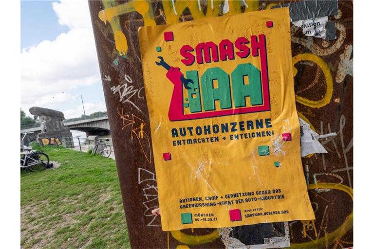 Ein gelbes Plakat mit der Aufschrift „Smash IAA Autokonzerne entmachten und enteignen!“ klebt an einer Wand in der Stadt. Foto: Peter Kneffel/dpa