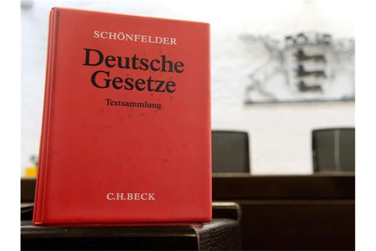 Ein Gesetzbuch steht vor dem baden-württembergischen Landeswappen. Foto: Sebastian Kahnert/dpa/Symbolbild