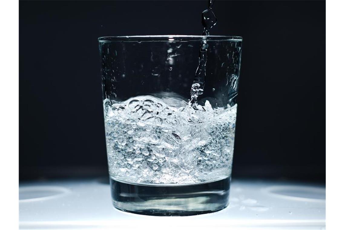 Ein Glas wird mit Mineralwasser befüllt. Foto: picture alliance / dpa/Symbolbild