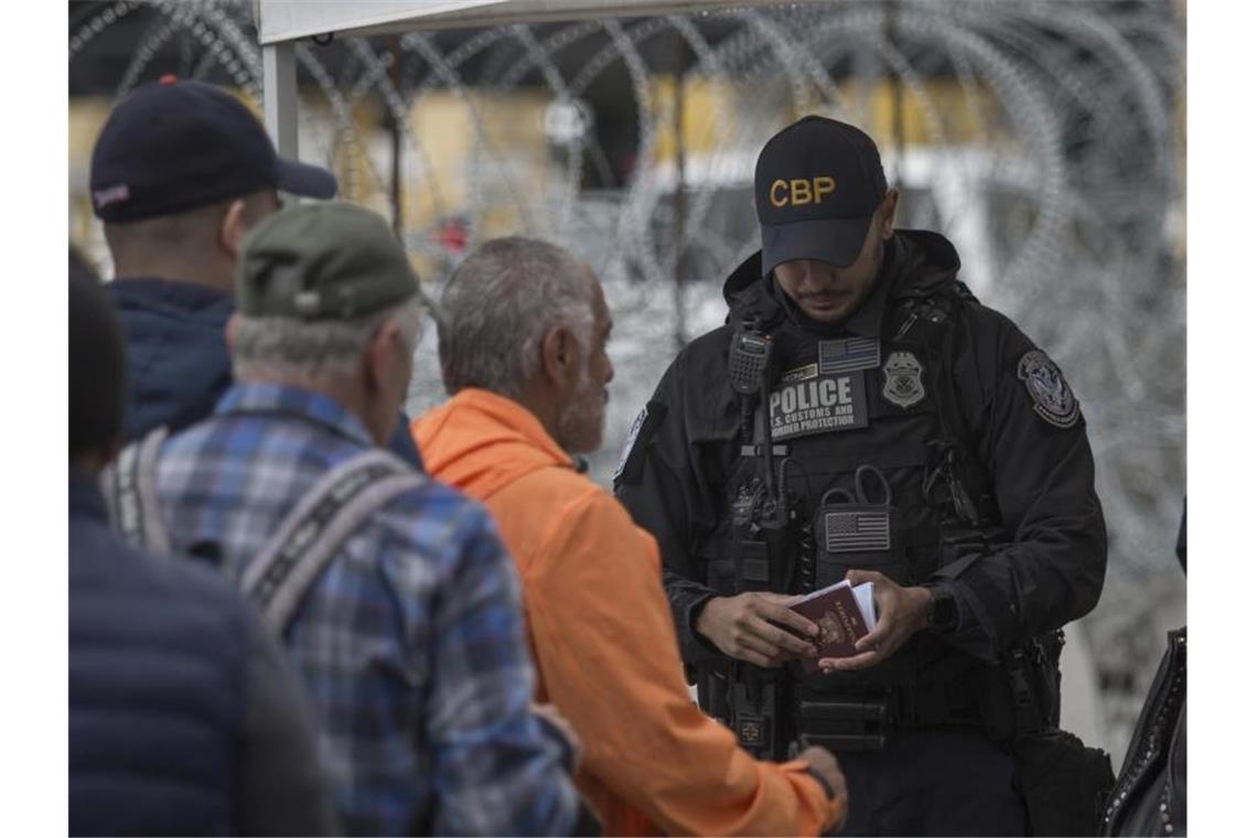 USA machen Grenze zu Mexiko weitgehend dicht Ein Grenzbeamter kontrolliert in Tijuana am Grenzübergang zwischen Mexiko und den USA einen Pass. Foto: Omar Martínez/dpa