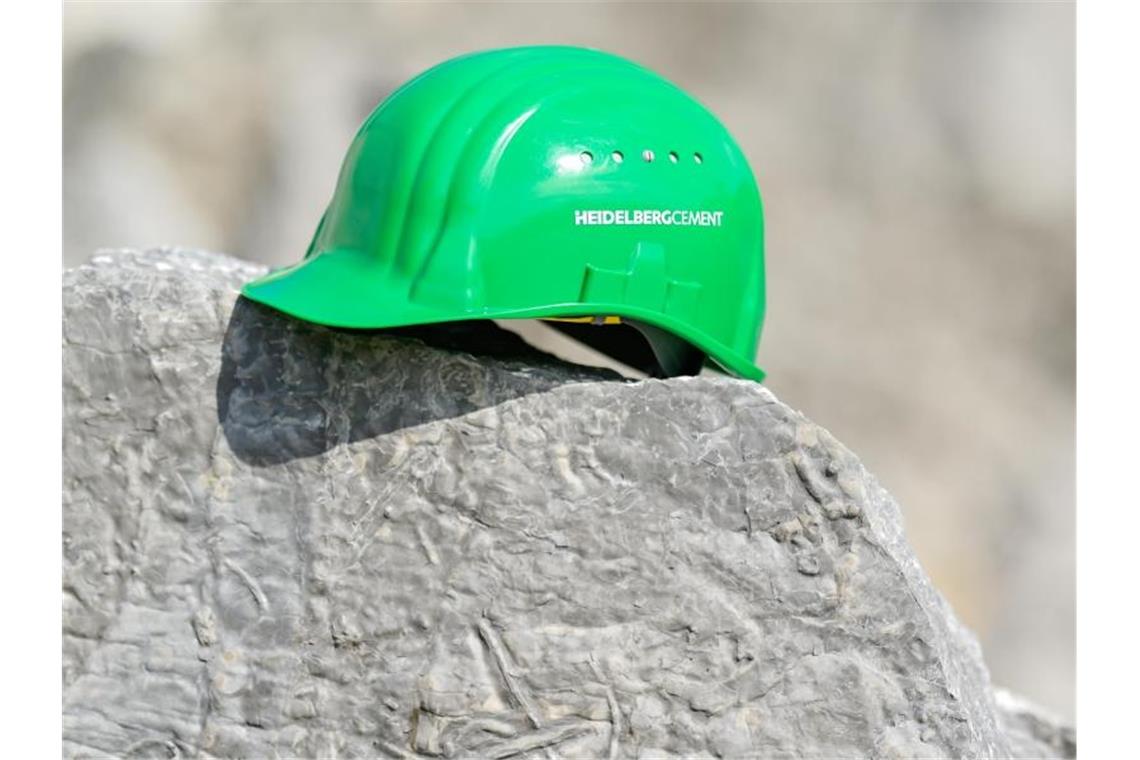 Führungswechsel bei HeidelbergCement Ein grüner Arbeitshelm mit der Aufschrift „HeidelbergCement“ liegt im Steinbruch. Foto: Uwe Anspach/dpa