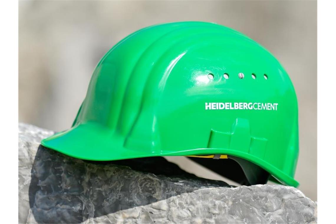 Ein grüner Arbeitshelm mit der Aufschrift „HeidelbergCement“. Foto: Uwe Anspach/dpa/Archivbild