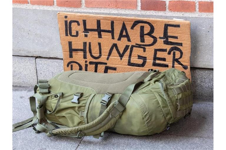 Ein grüner Rucksack vor einem Pappschild mit der Aufschrift „Ich habe Hunger“. Foto: Peter Kneffel/dpa/Symbolbild