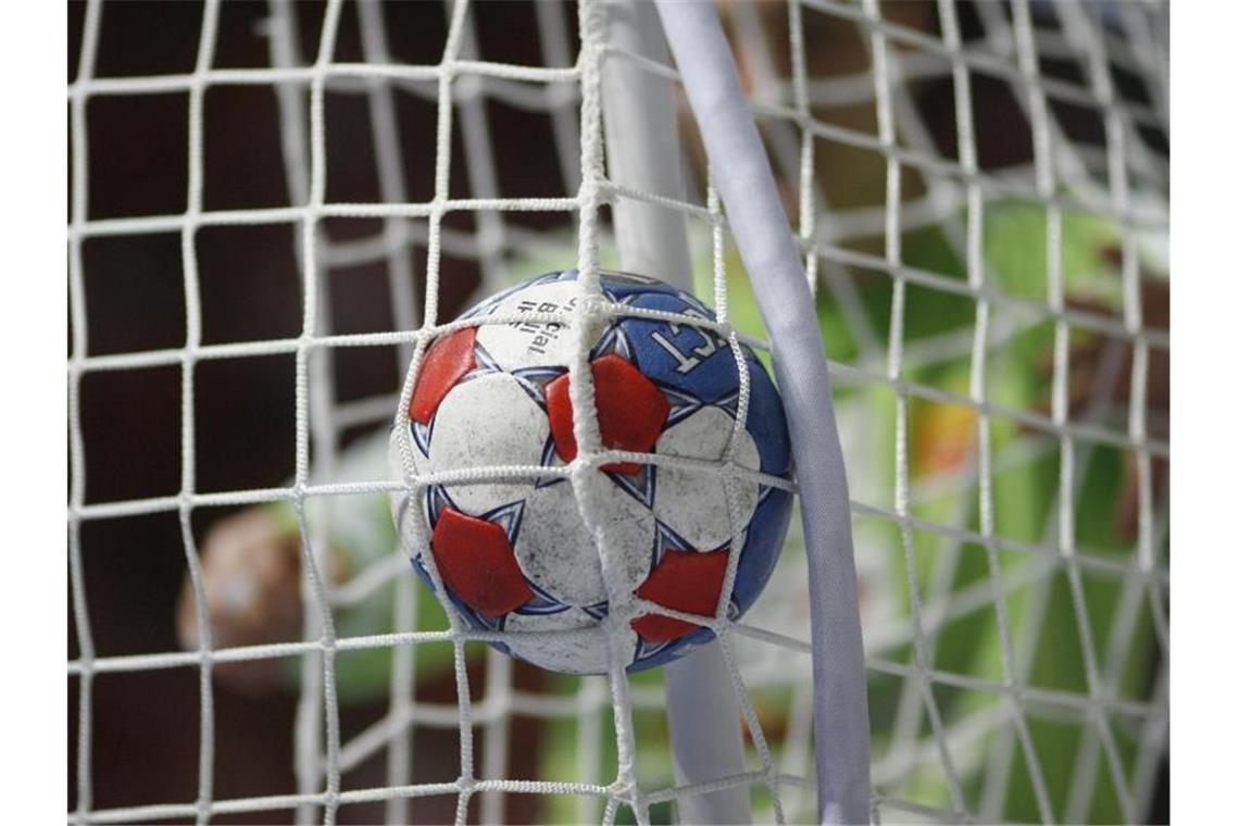 Ein Handball fliegt durch das Netz. Foto: Jens Wolf/dpa/Symbolbild