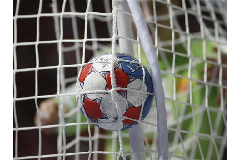 Ein Handball fliegt durch das Netz. Foto: Jens Wolf/dpa/Symbolbild