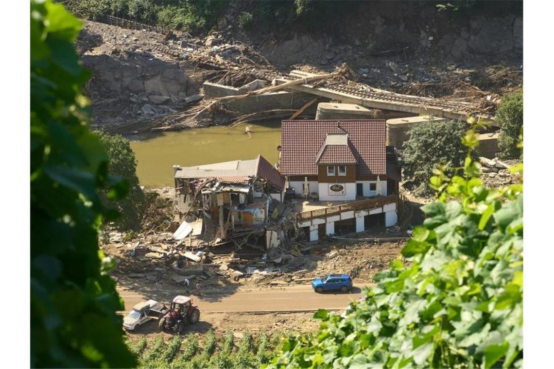 Ein Haus in Marienthal ist nach dem Hochwasser vollkommen aufgerissen, dahinter ist eine zerstörte Brücke zu sehen. Foto: Thomas Frey/dpa