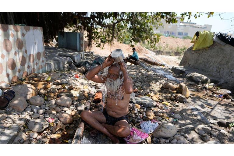 Ein heiliger Mann kühlt sich an einem heißen Tag in der indischen Stadt Jammu mit Wasser ab.