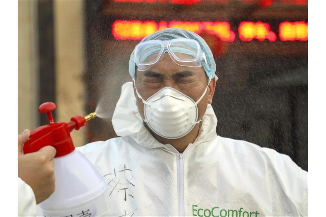 Ein Helfer in einer Quarantänestation in Wuhan wird desinfiziert. Foto: -/CHINATOPIX/AP/dpa