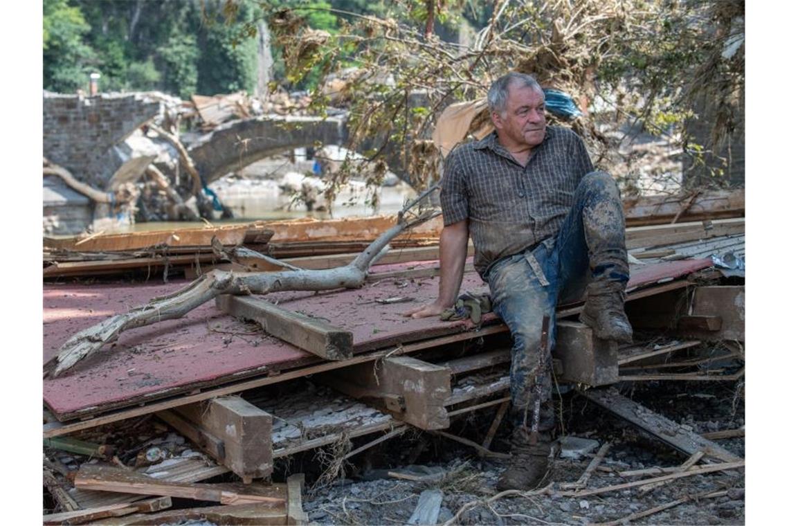 Hilfe für Flutopfer: Bund und Länder geben viele Millionen Ein Helfer ruht sich auf Treibgut und Trümmern aus. Zahlreiche Häuser in dem Ort wurden komplett zerstört oder stark beschädigt. Foto: Boris Roessler/dpa