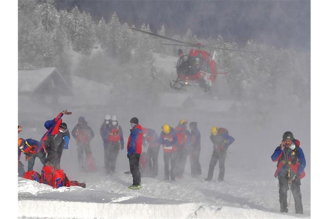 Ein Helikopter landet hinter Helfern der Bergrettung. Foto: Thomas Sehr/dpa