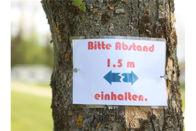 Ein Hinweisschild mit den Abstandsregeln, die auch auf Campingplätzen einzuhalten sind, hängt an einem Baum. Foto: Matthias Bein/dpa-Zentralbild/dpa/Symbolbild