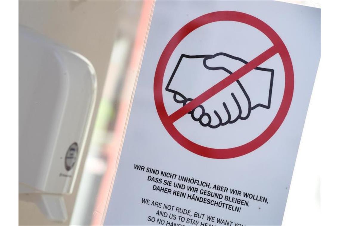 Ein Hinweisschild mit der Aufforderung, sich nicht die Hände zu schütteln, hängt an der Eingangstür des Standesamtes in Greifswald. Foto: Stefan Sauer/dpa