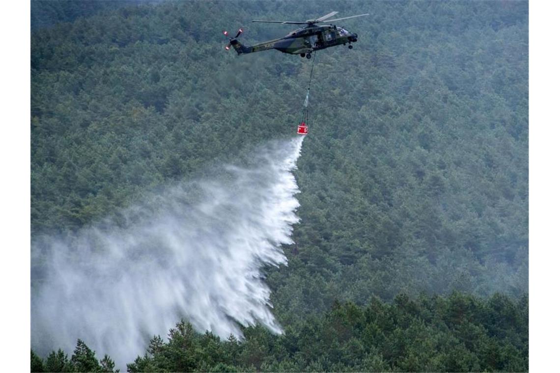 Hoffen auf Regen in Lübtheen Ein Hubschrauber der Bundeswehr vom Typ NH90 mit einem Löschwasser-Behälter wirft über einer Brandstelle Löschwasser ab. Foto: Jens Büttner