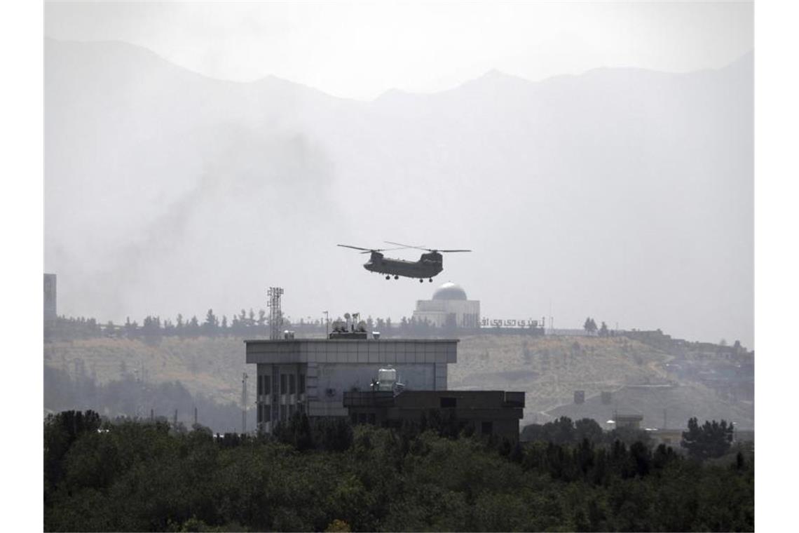 Taliban im Präsidentenpalast in Kabul Ein Hubschrauber der USA vom Typ Chinook fliegt über der US-Botschaft in Kabul. Foto: Rahmat Gul/AP/dpa