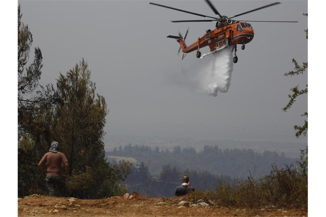 Ein Hubschrauber wirft Wasser über einem Feuer im Dorf Galatsonas auf der griechischen Insel Euböa ab. Foto: Lefteris Pitarakis/AP/dpa