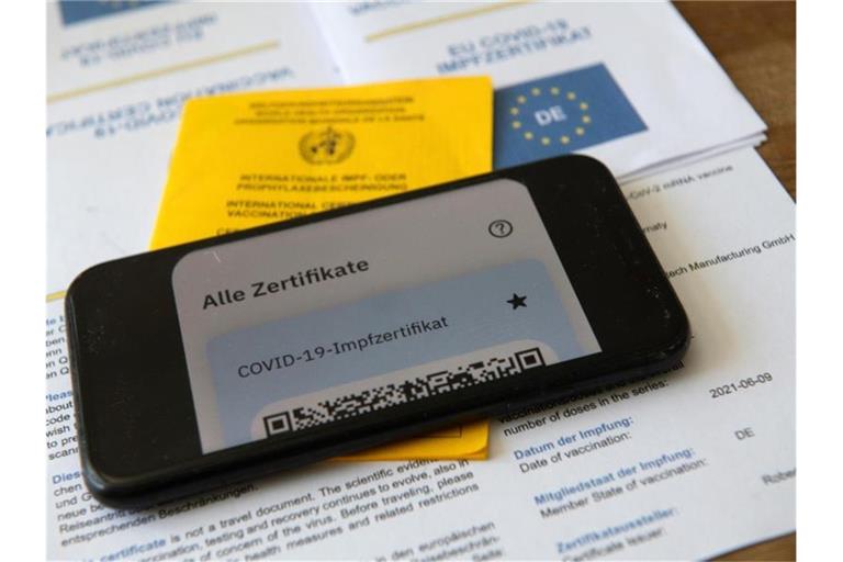 Ein Impfpass und ein Smartphone, auf dem die App CovPass läuft. Foto: Stefan Puchner/dpa/Illustration