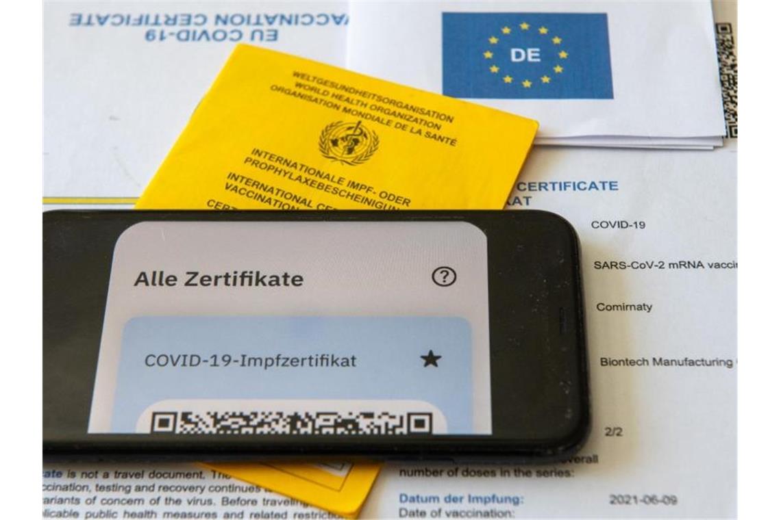 Ein Impfpass und ein Smartphone liegen auf einem Impfzertifikat. Foto: Stefan Puchner/dpa/Symbolbild