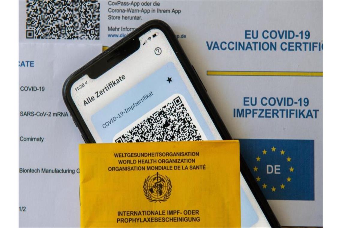 Ein Impfpass und ein Smartphone mit der CovPass-App liegen auf einem Impfzertifikat. Foto: Stefan Puchner/dpa/Symbolbild