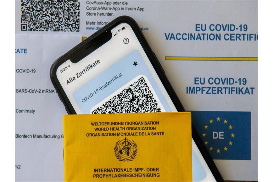 2G-Regel für Ungeimpfte soll ab Mittwoch in Kraft treten Ein Impfpass und ein Smartphone mit der CovPass-App liegen auf einem Impfzertifikat. Foto: Stefan Puchner/dpa/Symbolbild