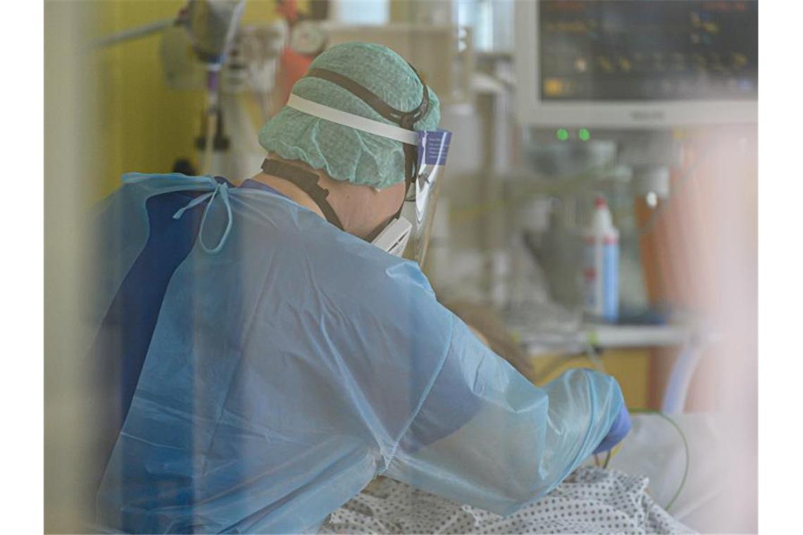 Ein Intensivpfleger ist auf der Covid-19 Intensivstation mit der Versorgung von Corona-Patienten beschäftigt. Foto: Robert Michael/dpa-Zentralbild/dpa