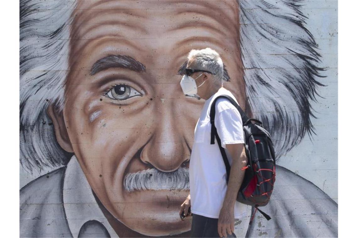 Ein israelischer Mann, der einen Mund- und Nasenschutz trägt, geht an einem Wandbild vorbei, das Albert Einstein zeigt. Foto: Sebastian Scheiner/AP/dpa