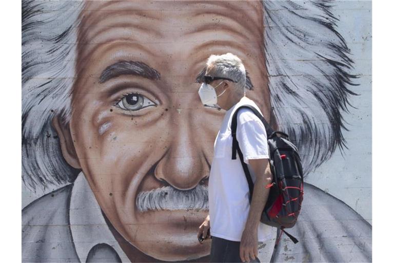 Ein israelischer Mann, der einen Mund- und Nasenschutz trägt, geht an einem Wandbild vorbei, das Albert Einstein zeigt. Foto: Sebastian Scheiner/AP/dpa