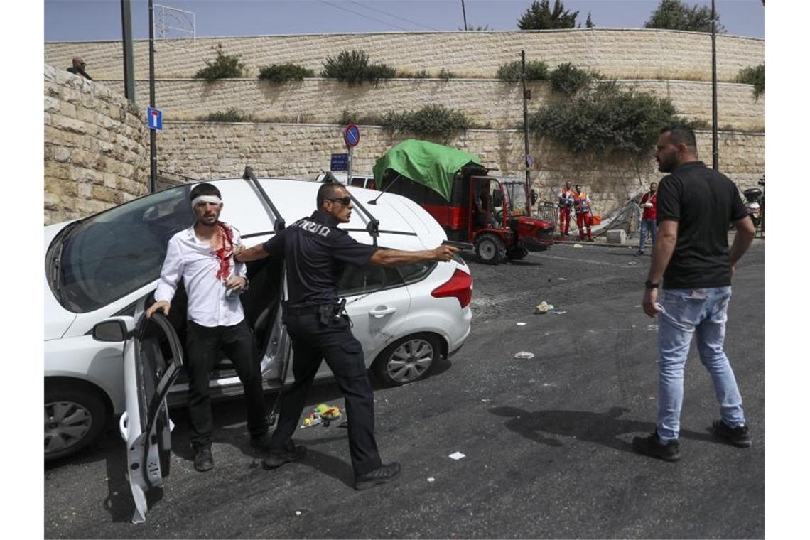 Ein israelischer Polizist schützt einen jüdischen Fahrer, der von palästinensischen Demonstranten in der Nähe der Altstadt von Jerusalem angegriffen wurde. Foto: Ohad Zwigenberg/Haaretz/AP/dpa