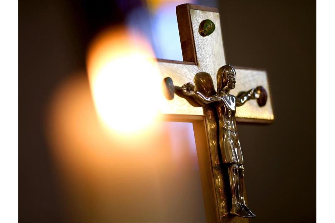 Corona-Regeln in Deutschland werden leicht gelockert Ein Jesuskreuz und eine brennende Kerze in der römisch-katholischen Kathedralkirche Sankt Sebastian in Magdeburg. Foto: Ronny Hartmann/dpa