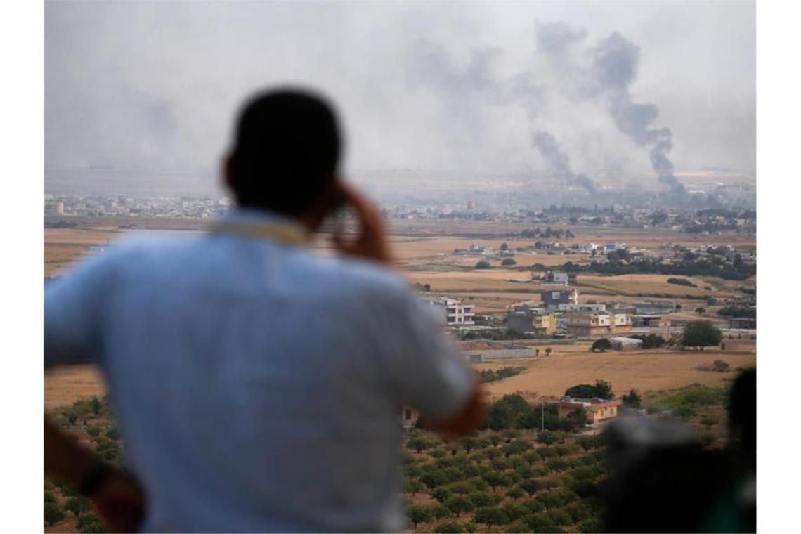 Ein Journalist beobachtet den Rauch, der nach einem türkischen Bombardement über der syrischen Stadt Ras al-Ain aufsteigt. Foto: Lefteris Pitarakis/AP/dpa