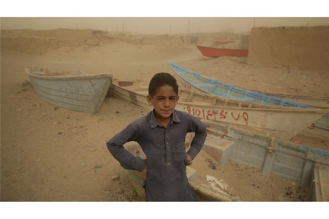 Ein Junge im Iran steht vor alten Booten, wo einst ein See war.