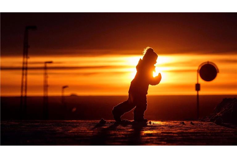 Ein Junge läuft bei Sonnenuntergang über eine Straße in Nuuk in Grönland.