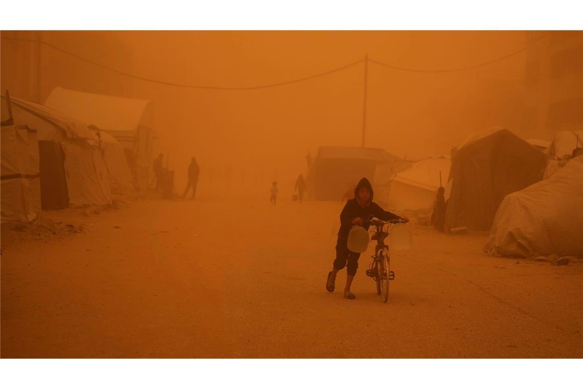Ein Junge schiebt sein Fahrrad durch einen Sandsturm in Chan Junis.