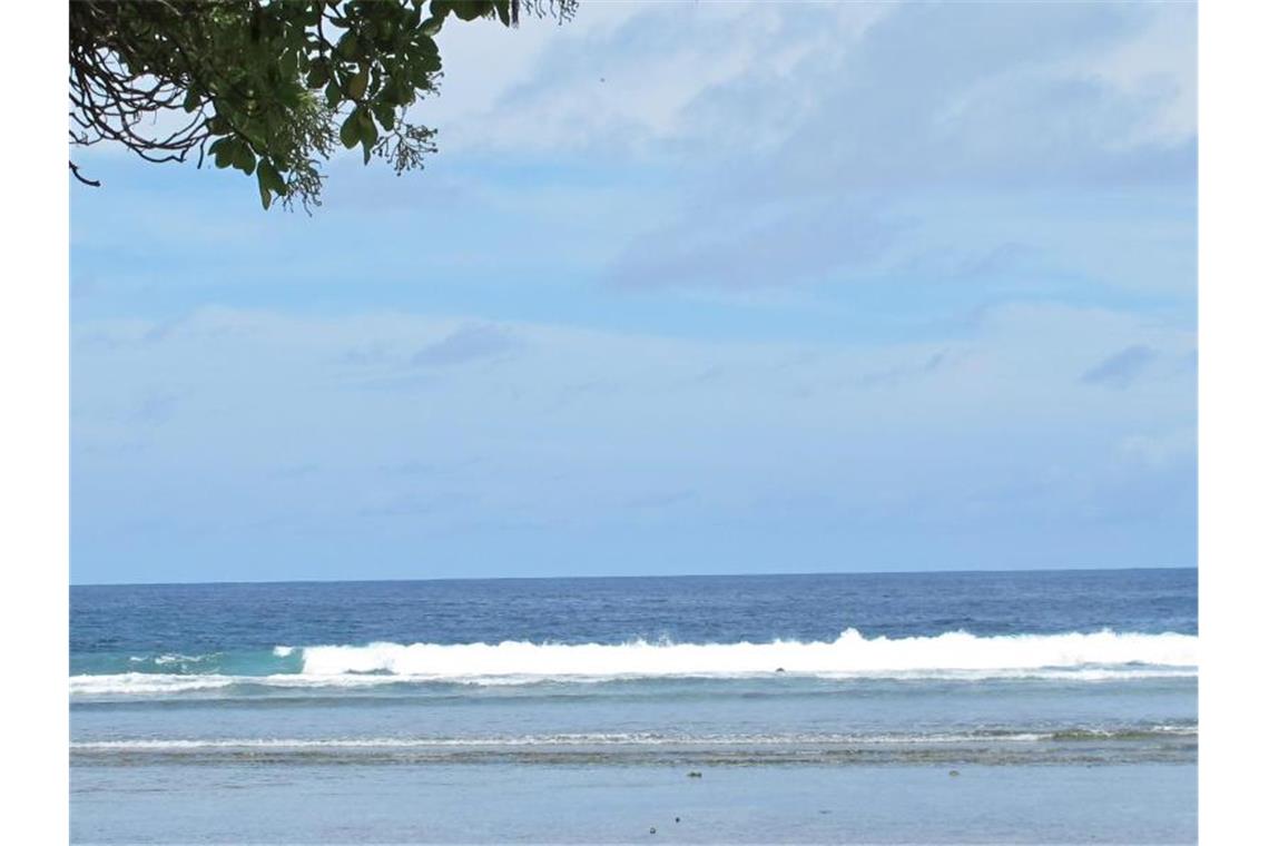 Ein Junge sitzt am Sandstrand auf der Fidschi-Insel Kiribati neben Abfällen. Das Institute for Economics and Peace stellt eine Studie zu ökologischen Bedrohungen und Klimaflüchtlingen vor. Foto: Christiane Oelrich/dpa