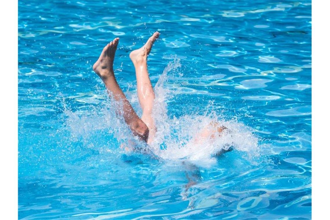 Ein Junge wird von seinem Vater ins Wasser geworfen. Foto: Daniel Bockwoldt/dpa/Symbolbild