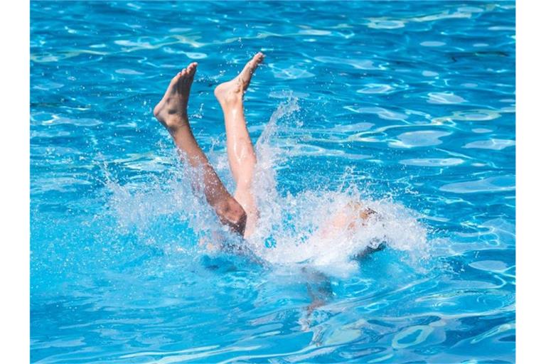 Ein Junge wird von seinem Vater ins Wasser geworfen. Foto: Daniel Bockwoldt/dpa/Symbolbild