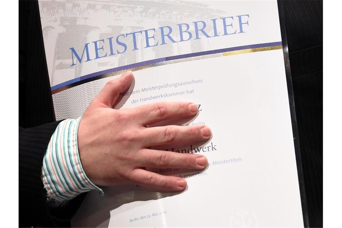 Grün-Schwarz einigt sich auf Meisterprämie Ein junger Mann freut sich bei der Meisterfeier über seinen Meisterbrief. Foto: Britta Pedersen/zb/dpa/Archivbild