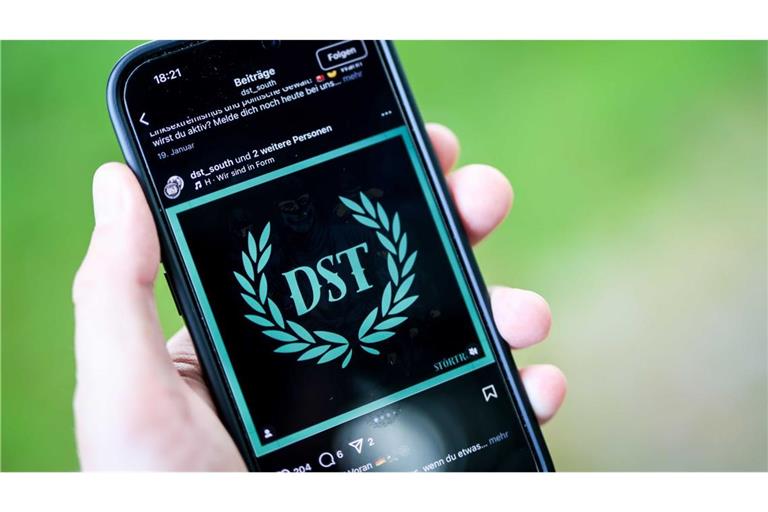 Ein junger Mann hält ein Smartphone in der Hand, auf der die Instragram-Seite von „Sturmtrupp Süd“ zu sehen ist (Symbolbild).