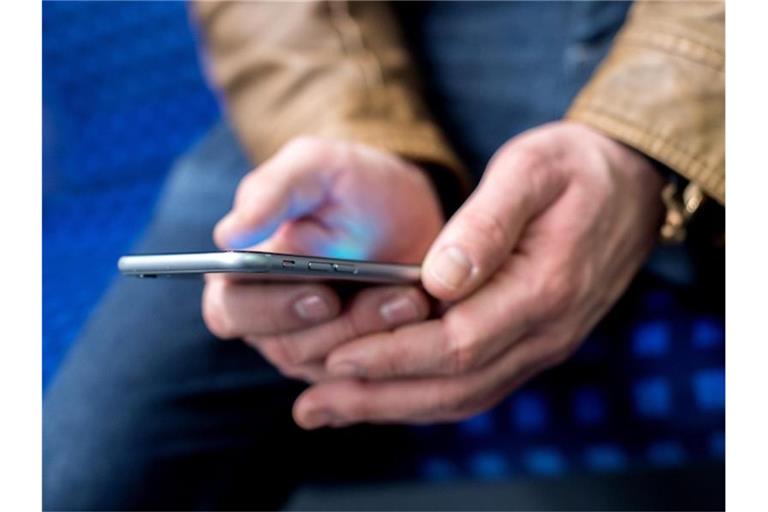 Ein junger Mann hält sein Smartphone in den Händen. Foto: Hauke-Christian Dittrich/dpa/Archivbild