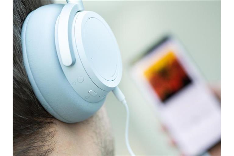 Ein junger Mann hört mit Kopfhörern Musik von seinem Smartphone. Foto: Franziska Gabbert/dpa-tmn/dpa